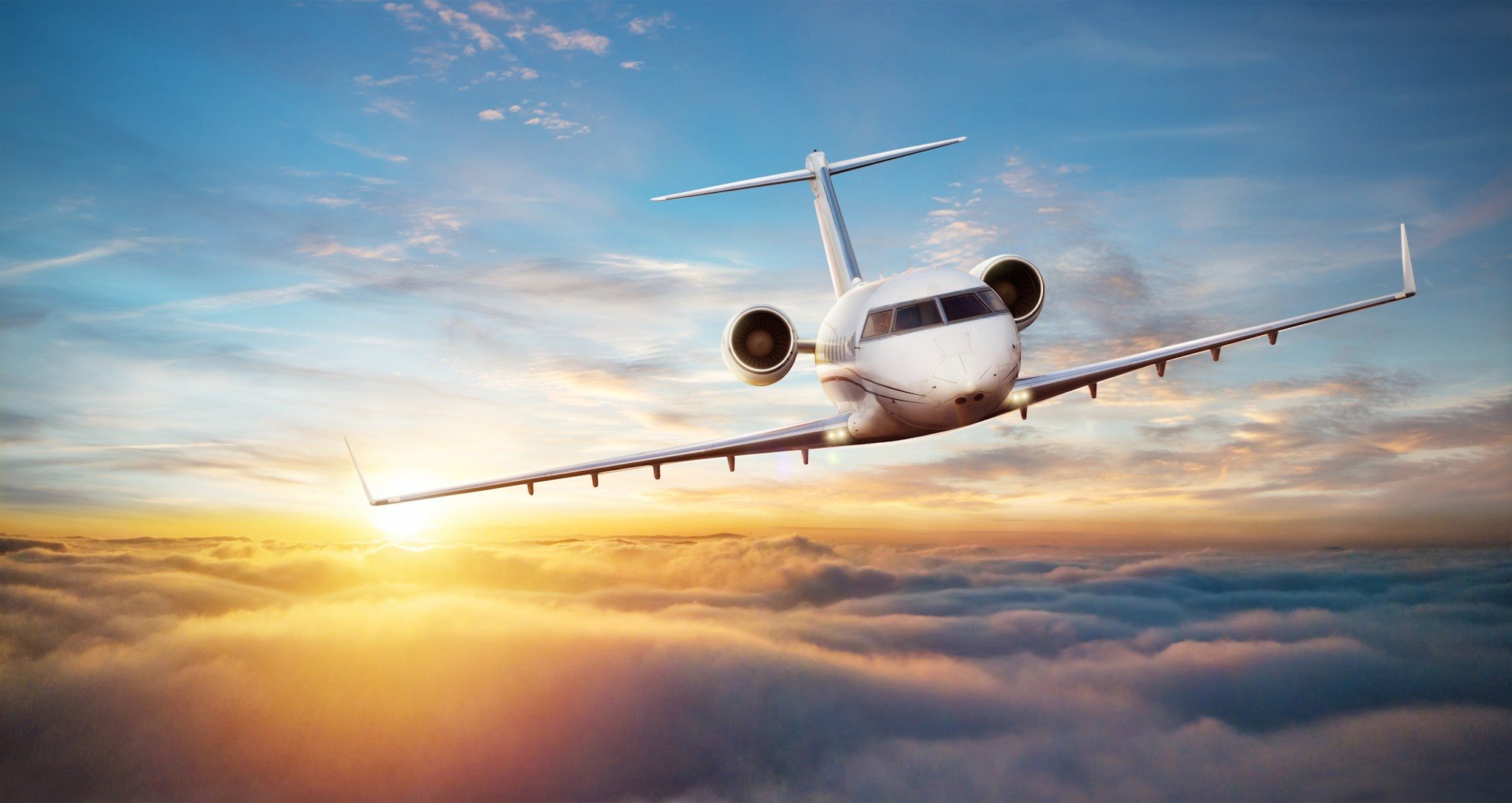 Business jet flying above golden clouds at sunset